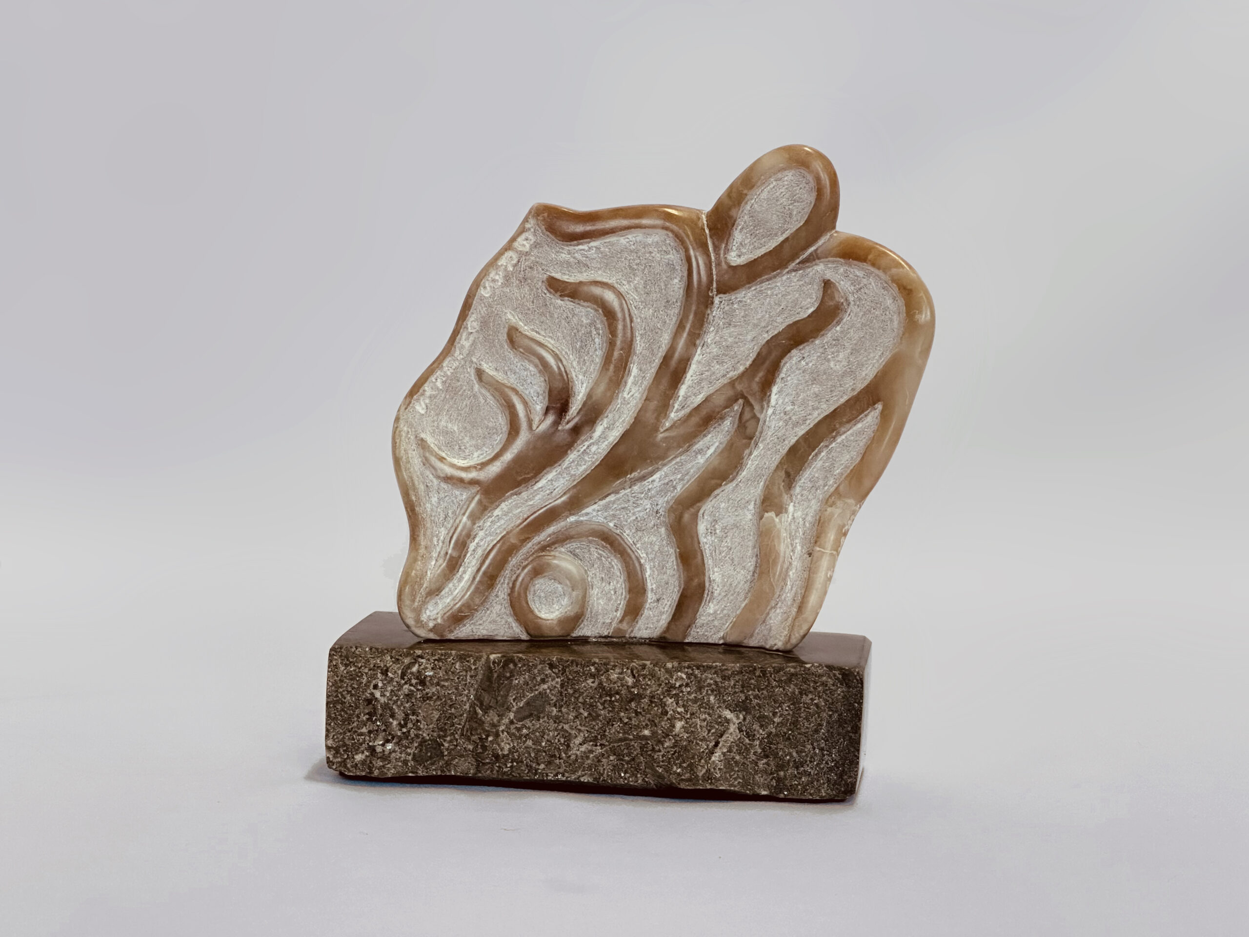 Sculpture abstraite aux courbes ondulantes, en pierre beige veinée de brun, montée sur une base en pierre foncée.